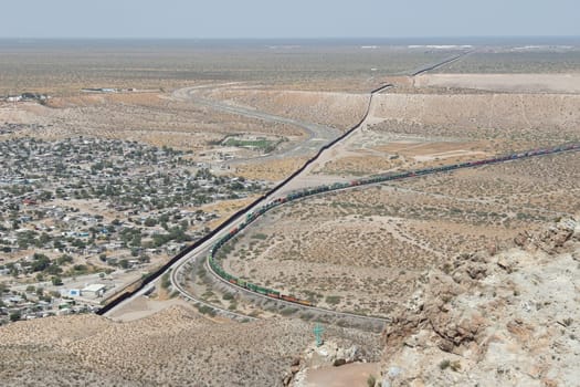 Border wall or fence and train, New Mexico running parallel to freight train on U.S. side of border