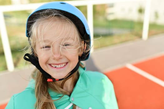 Girl in a blue helmet roller skates in the stadium