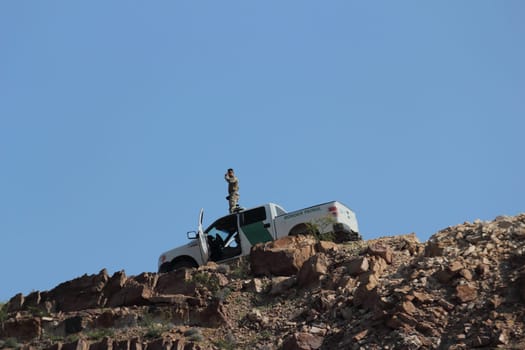 Customs and border protection officer. Unrecognizable person on top of a mountain.