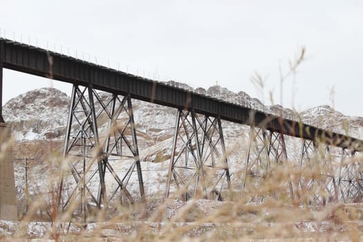 Old fashioned metal railway bridges leading to snowy mountains in El Paso, Texas.