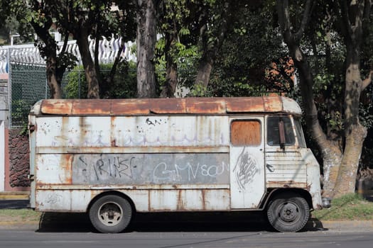 Old rusty bus on the side of the street in Mexico City.