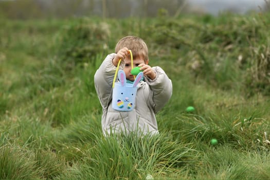 Boy collects the eggs in a basket Easter
