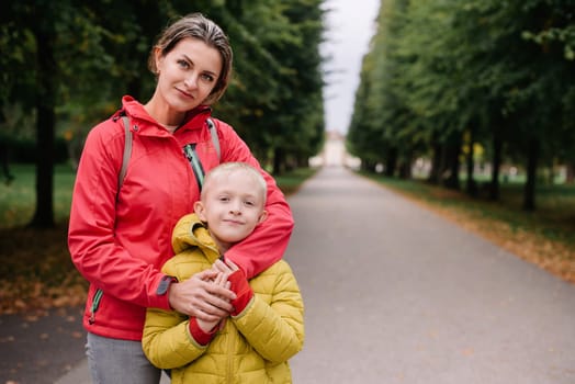 mother and son stand hugging in the park in the fall. happy mother playing with her son in the park. Mother hugs her son while standing in the forest in autumn.