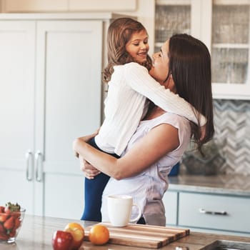 Cuddles with her cutie. a happy mother hugging her cute little girl in the kitchen at home