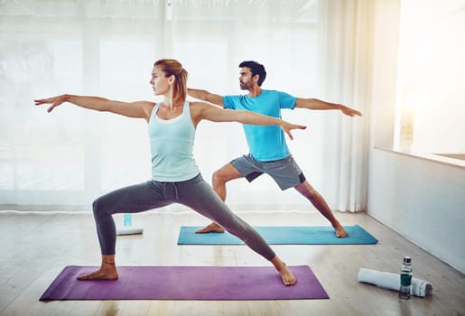 Strengthen your body and your bond. a couple practising yoga at home