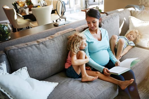 She enjoys learning more about the babies development. a pregnant woman spending time with her children at home