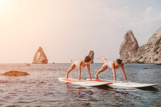 Woman sup yoga. Middle age sporty woman practising yoga pilates on paddle sup surfboard. Female stretching doing workout on sea water. Modern individual hipster outdoor summer sport activity