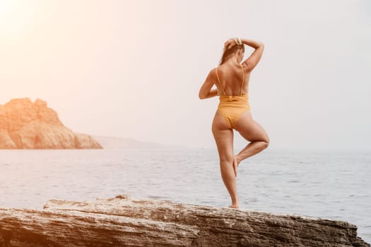 Woman meditating in yoga pose silhouette at the ocean, beach and rock mountains. Motivation and inspirational fit and exercising. Healthy lifestyle outdoors in nature, fitness concept.