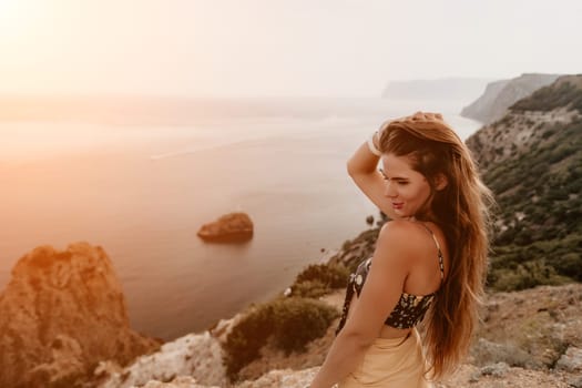 Woman travel sea. Happy tourist taking picture outdoors for memories. Woman traveler looks at the edge of the cliff on the sea bay of mountains, sharing travel adventure journey.