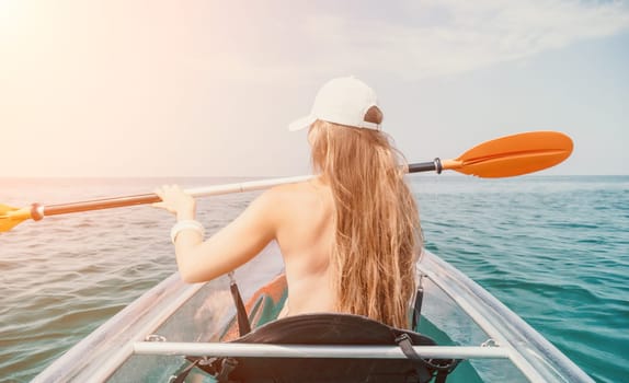 Woman in kayak back view. Happy young woman with long hair floating in transparent kayak on the crystal clear sea. Summer holiday vacation and cheerful female people having fun on the boat.