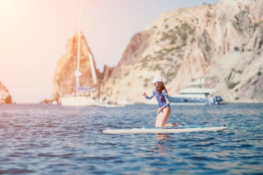 Woman sup yoga. Middle age sporty woman practising yoga pilates on paddle sup surfboard. Female stretching doing workout on sea water. Modern individual hipster outdoor summer sport activity