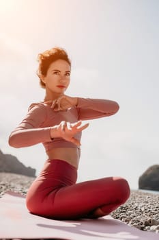 Young woman with long hair in white swimsuit and boho style braclets practicing outdoors on yoga mat by the sea on a sunset. Women's yoga fitness routine. Healthy lifestyle, harmony and meditation