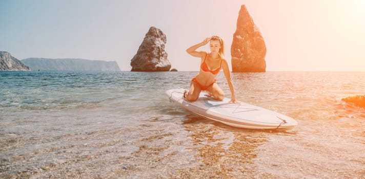 Close up shot of beautiful young caucasian woman with black hair and freckles looking at camera and smiling. Cute woman portrait in a pink bikini posing on a volcanic rock high above the sea