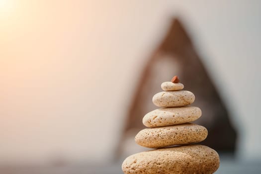 Pyramid stones on the seashore with warm sunset on the sea background. Happy holidays. Pebble beach, calm sea, travel destination. Concept of happy vacation on the sea, meditation, spa, calmness.