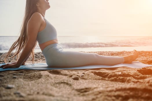 Middle aged well looking woman with black hair doing Pilates with the ring on the yoga mat near the sea on the pebble beach. Female fitness yoga concept. Healthy lifestyle, harmony and meditation.