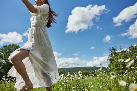 a woman in a light dress, in a chamomile field against the blue sky, runs away from the frame. Photo without a face. High quality photo