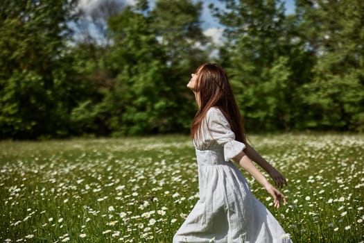 portrait of a free woman in a light dress in a chamomile field against the backdrop of hills enjoying nature. High quality photo