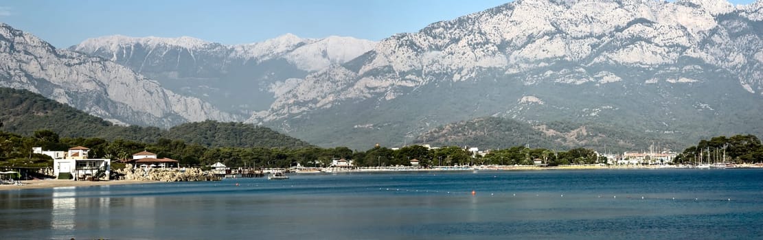 Kemer Antalia nice view of the sea. Beach Kemer Antalia with sand and mountains, the sea with the ship. Beautiful harbor near the sandy beach.