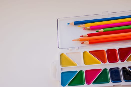 Kid's desk with colorful pencils, brushes and watercolors, top view with copy space