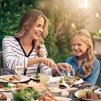 Let Mommy help you with that. a mother and daughter eating lunch together outdoors
