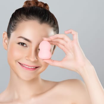 Glamorous beautiful female model applying cushion powder for facial makeup concept. Portrait of flawless perfect cosmetic skin woman put powder puff on her face in isolated background.