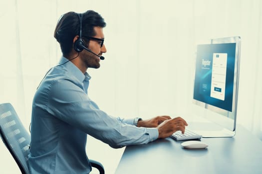 Male call center operator or telesales representative siting at his office desk wearing headset and engaged in conversation with client providing customer service support or making a sale. fervent