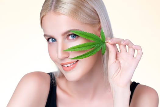 Closeup personable beautiful white blond hair with perfect smooth makeup skin hold cannabis green hemp in isolated background for natural CBD skincare treatment with perfect facial gesture expression.