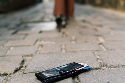 Photo of the sidewalk and legs of man who lost a black leather wallet while walking