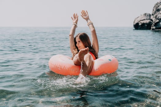 Woman summer sea. Happy woman swimming with inflatable donut on the beach in summer sunny day, surrounded by volcanic mountains. Summer vacation concept