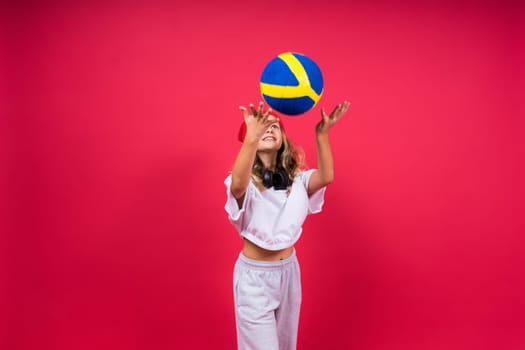 Portrait of cute eight year old girl in volleyball outfit isolated on a red yellow background