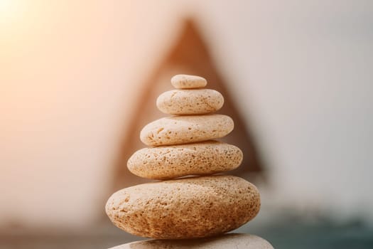 Pyramid stones on the seashore with warm sunset on the sea background. Happy holidays. Pebble beach, calm sea, travel destination. Concept of happy vacation on the sea, meditation, spa, calmness.