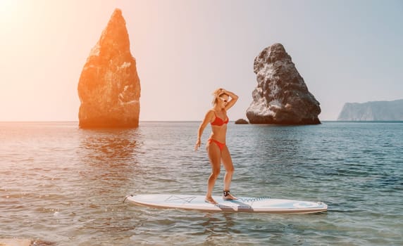 Close up shot of beautiful young caucasian woman with black hair and freckles looking at camera and smiling. Cute woman portrait in a pink bikini posing on a volcanic rock high above the sea