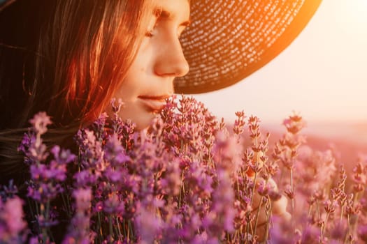 Close up portrait of young beautiful woman in a white dress and a hat is walking in the lavender field and smelling lavender bouquet.