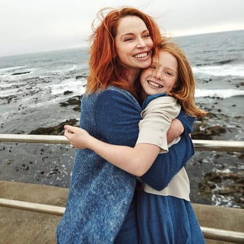 Big hearts deserve big hugs. a mature woman and her young daughter at the waterfront