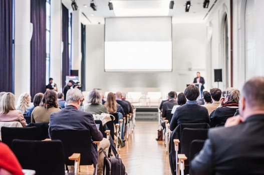 Speaker giving a talk in conference hall at business event. Rear view of unrecognizable people in audience at the conference hall. Business and entrepreneurship concept