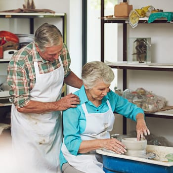 Pottering around in the workshop. a senior couple making a ceramic pot together in a workshop