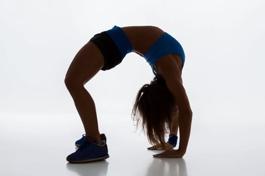 Sport and active lifestyle. Sporty flexible girl fitness woman in sportswear doing stretching exercise on light background. silhouette