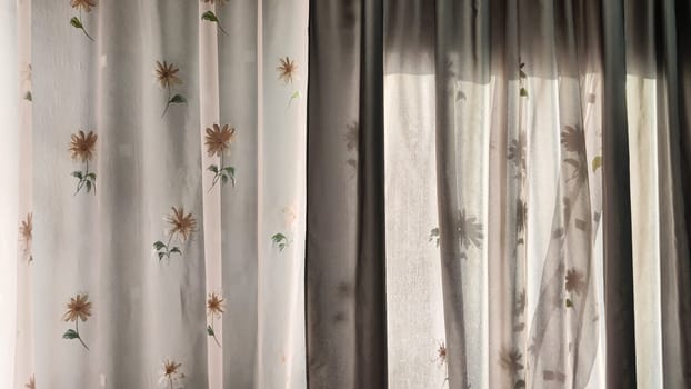 Transparent tulle curtains with floral pattern on the window and light behind the glass. Abstract Background, texture and copy space