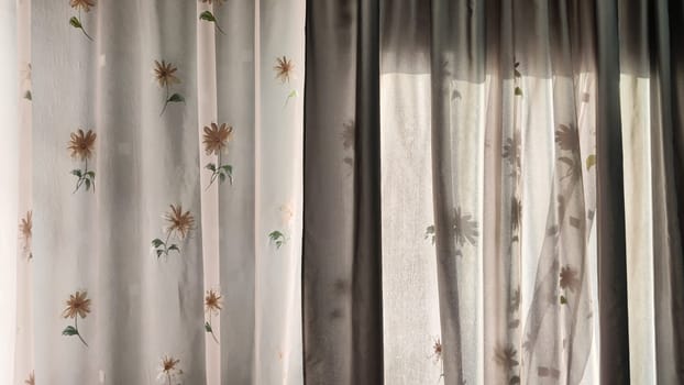 Transparent tulle curtains with floral pattern on the window and light behind the glass. Abstract Background, texture and copy space