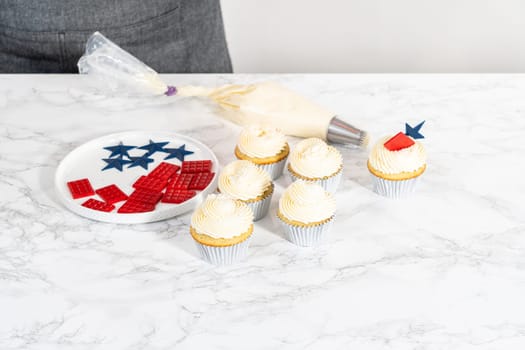 Decorating lemon cupcakes with patriotic blue chocolate star and red mini chocolate.