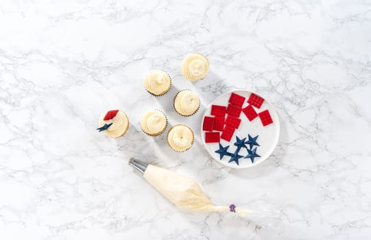 Flat lay. Decorating lemon cupcakes with patriotic blue chocolate star and red mini chocolate.