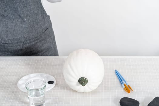 Painting panda face with black acrylic paint to make panda pumpkin for Halloween.