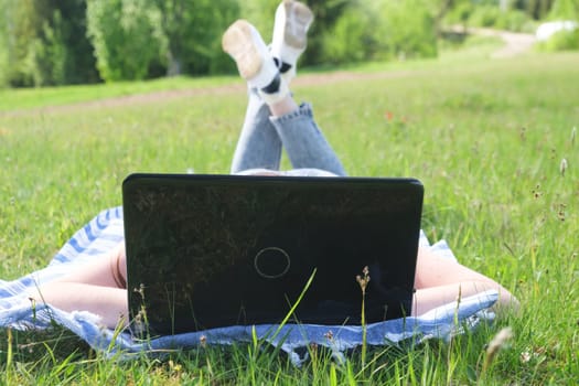 Attractive woman using laptop in the park lying on the green grass. Person with laptop in park. download image