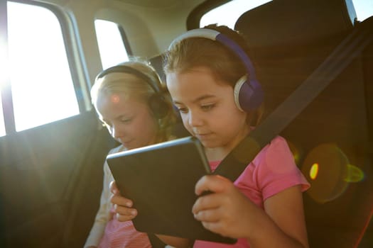 Technological travel packs for kids. a two little girls traveling in a car