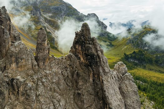 High mountain valley near Giau pass in Dolomites with green meadows for pastures under cloudy sky. View through rocky peaks on vast mountain pastures