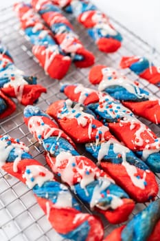 Drizzling white glaze on top of patriotic cinnamon twists. and decorating with star sprinkles.