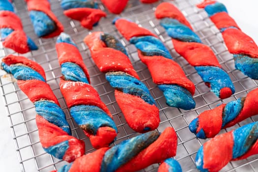 Drizzling white glaze on top of patriotic cinnamon twists. and decorating with star sprinkles.