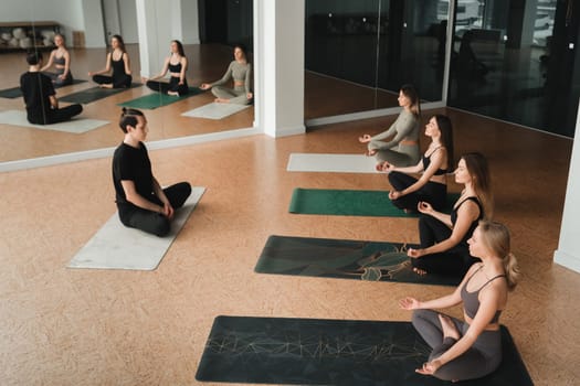 a group of girls do yoga in the gym under the guidance of a coach.