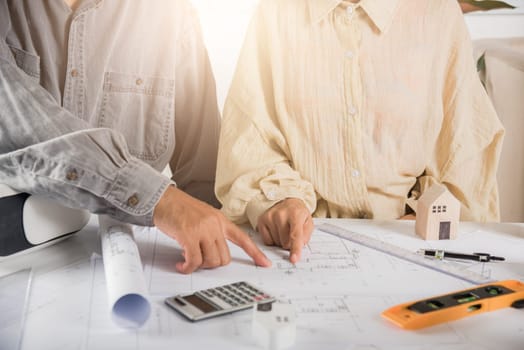 Two engineers pointing at drawings project, Architect team meeting consult and work for architectural construction project working with partner and engineering after editing on blueprint paper plans