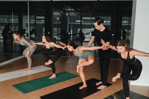 a group of girls do yoga in the gym under the guidance of a coach.